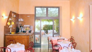 Un restaurante con vistas al exterior, que cuenta con una zona de bar con una máquina de café y una exhibición de tazas y platillos.