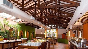 A spacious buffet area with multiple serving tables, a high wooden ceiling with exposed beams, and a brick floor. - Hotel Estância Barra Bonita (Barra Bonita)