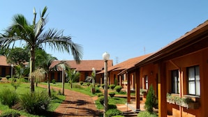 A pathway leading to a building with a tiled roof and a well-maintained garden with palm trees and shrubs. - Hotel Estância Barra Bonita (Barra Bonita)