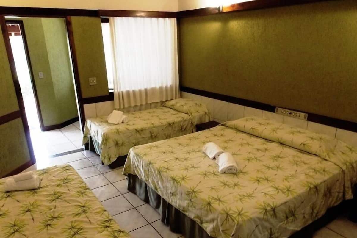 A hotel room with three beds, each with a bamboo-patterned bedspread.