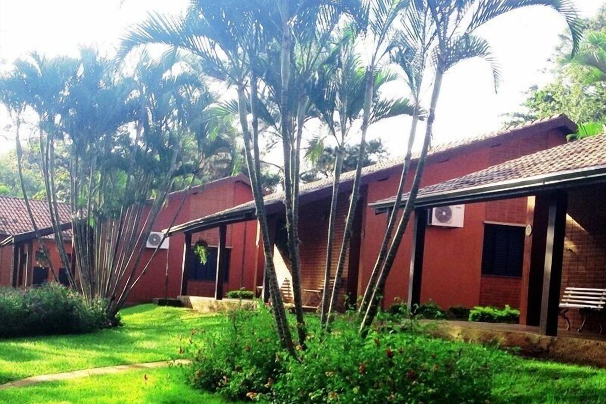 A row of red brick buildings with a covered walkway and lush greenery.