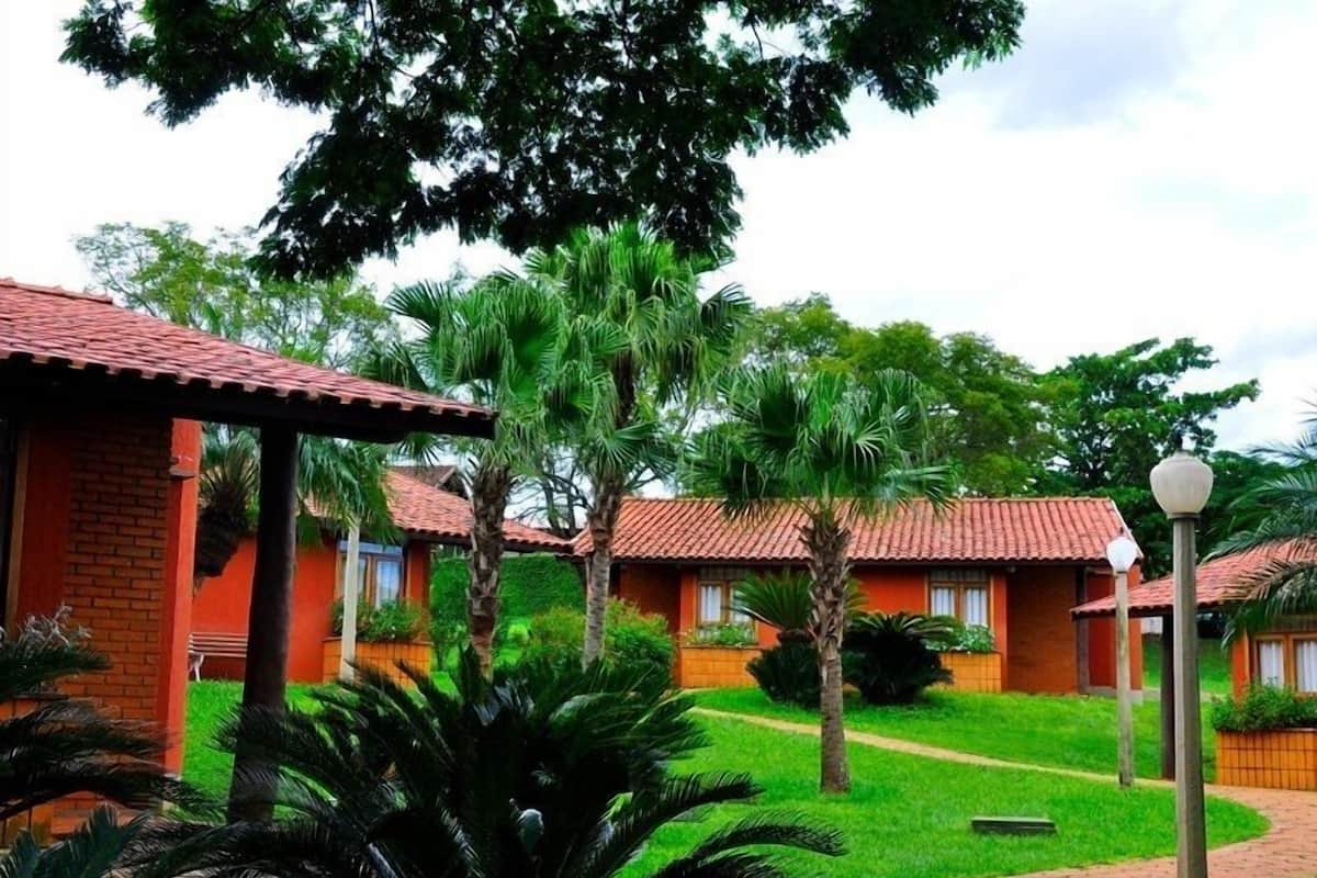 A row of red-roofed cottages with a well-maintained lawn and palm trees.