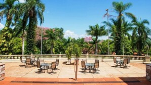 An outdoor seating area with tables and chairs, surrounded by palm trees and a clear blue sky. - Hotel Estância Barra Bonita (Barra Bonita)