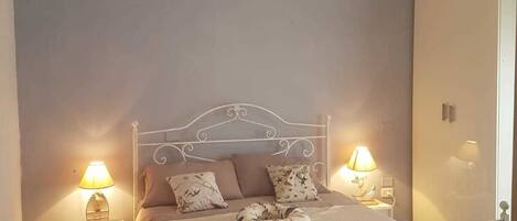 Ein Schlafzimmer mit einem Bett, zwei Nachttischen mit Lampen, einem Kleiderschrank und einem Fliesenboden.