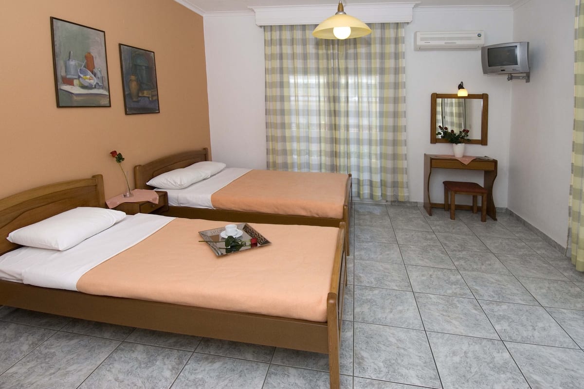 A hotel room with two beds, a desk with a chair, a television, and a mirror.