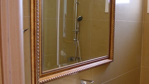 A bathroom with a large mirror, a white sink, and a shower. - Harisis Apartments (Katerini)