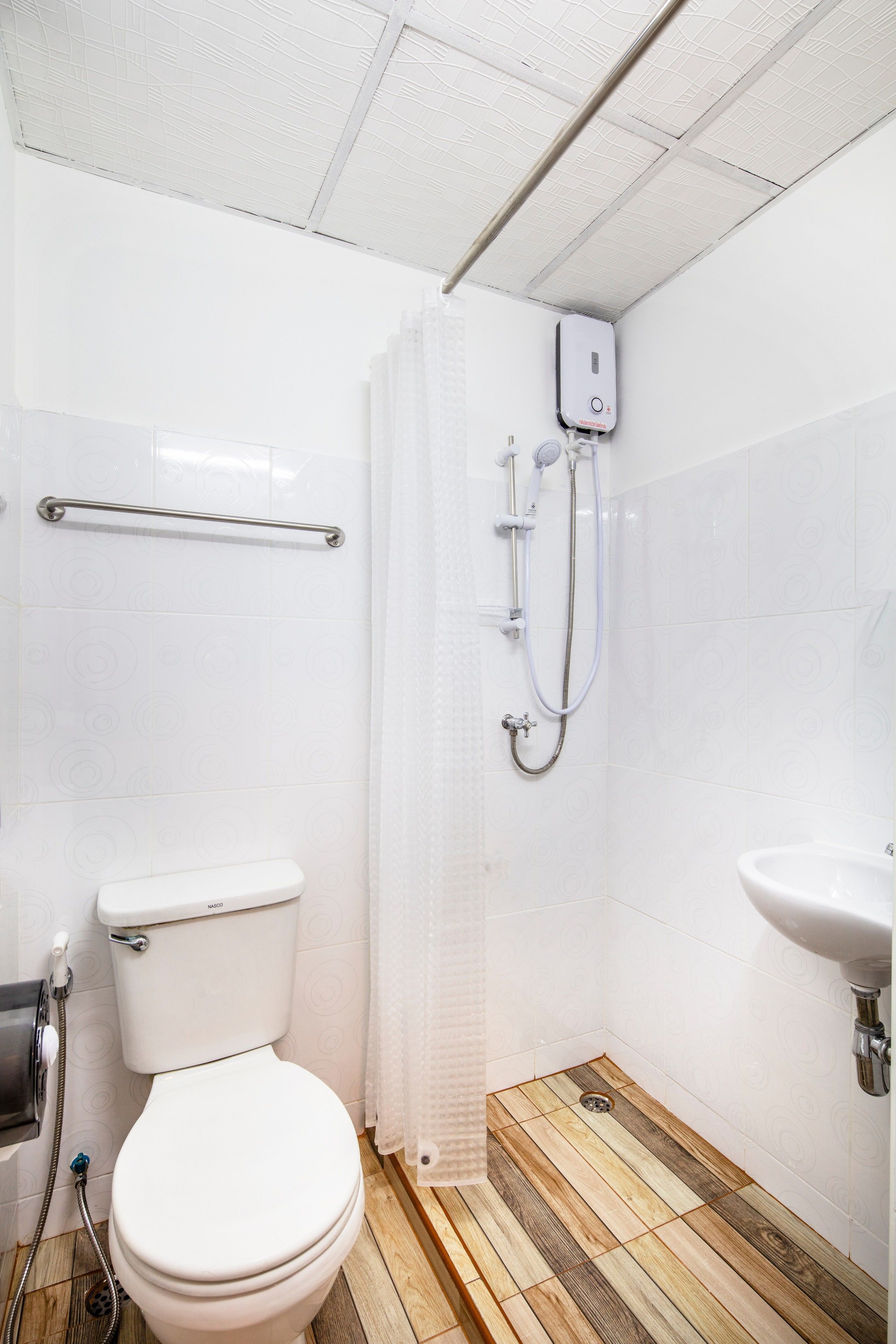 A bathroom with a toilet, shower, and sink.