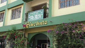 A multi-story building with a sign for Hotel Sinchula, featuring balconies with metal railings and a green and yellow facade. - Hotel Sinchula (Phuntsholing)
