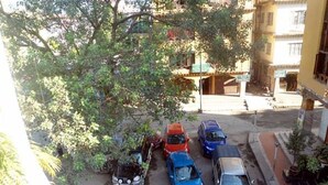 A street view with parked cars, a pedestrian, and buildings in the background. - Hotel Sinchula (Phuntsholing)