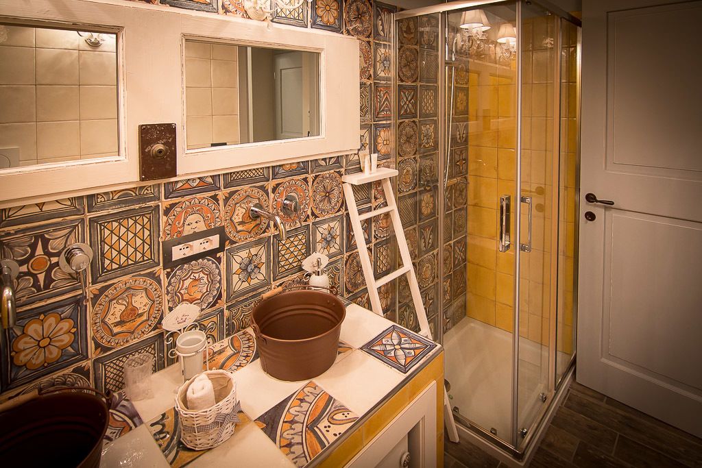 A bathroom with a tiled backsplash, a shower with glass doors, and a sink with a mirror above it.