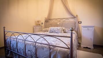 A bedroom with a four-poster bed, a nightstand, a bedside table, and a wardrobe.