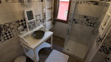 Ein Badezimmer mit weißem Waschtisch, einem großen Spiegel, einem Waschbecken und einer Dusche mit Glastür.