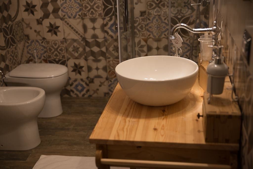 Un baño con tocador de madera, un lavamanos blanco y dos inodoros.