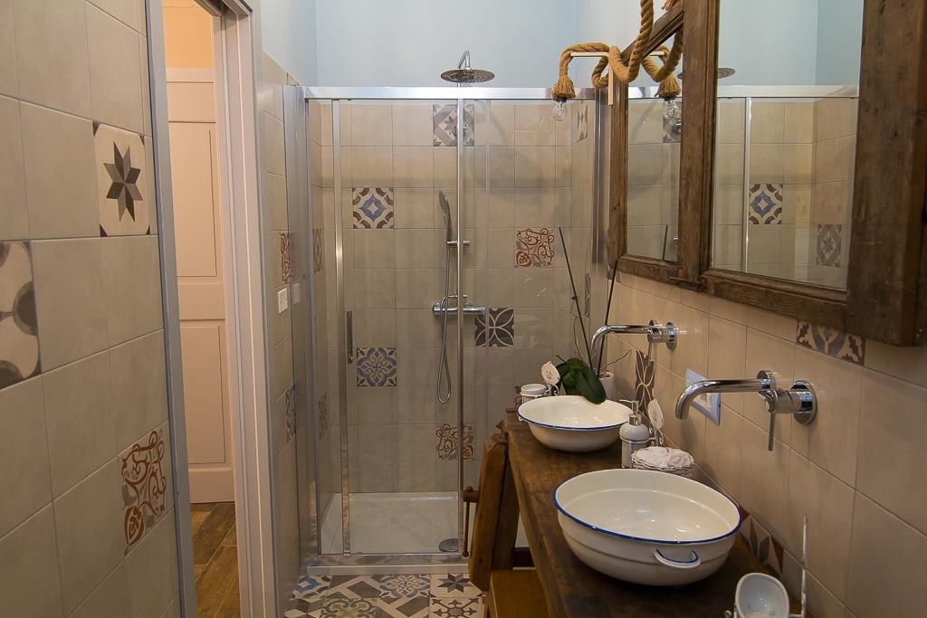 Un bagno con cabina doccia in vetro, un mobile bagno in legno con un lavabo capiente e uno specchio sopra il lavandino.