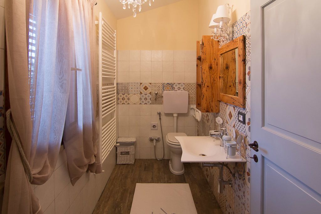 Une salle de bain équipée de toilettes, d’un lavabo et d’une douche. On y trouve également un porte-serviettes et un meuble en bois.