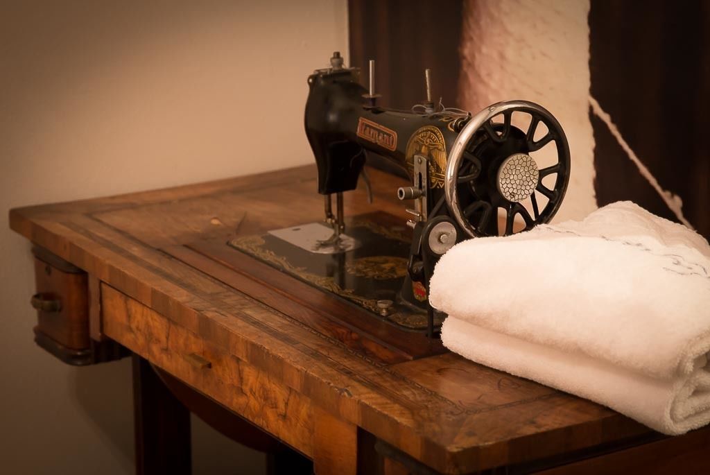 A vintage sewing machine on a wooden table with a folded white towel beside it.