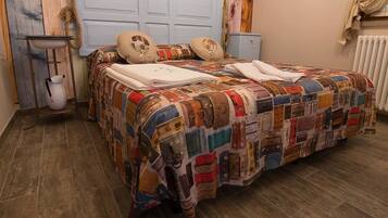 A bed with a patchwork quilt, a bedside table with a pitcher, and a blue headboard.