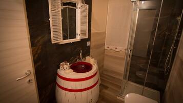 Un baño con un lavamanos de barril de madera, un espejo y un box de ducha.