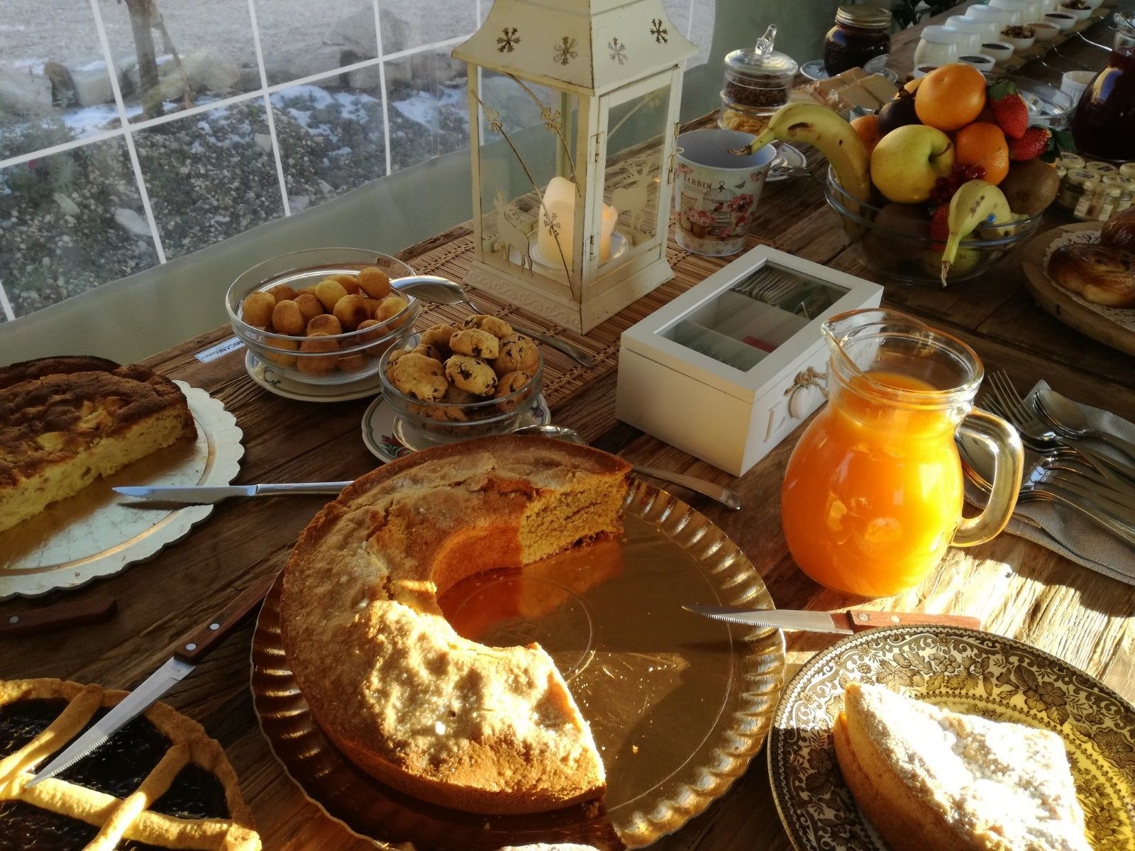 Une table de petit-déjeuner avec diverses pâtisseries, une tarte et un saladier de fruits.