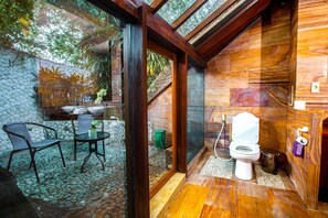 Ein Badezimmer mit Holzboden, Toilette in Weiß und einer Duschkabine.