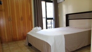 Ein Hotelzimmer mit Bett, Kleiderschrank und Blick nach außen.