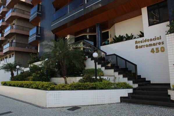 A modern residential building with a white facade, a staircase leading to the entrance, and a sign indicating the address as "Residencial Barramare 450".