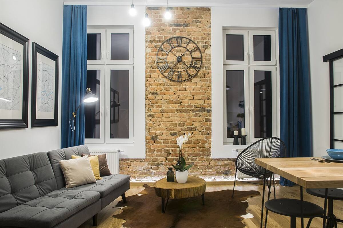 A modern living room with a brick wall, a large clock, a sofa, a dining table, and a coffee table.