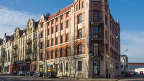 Un edificio a più piani con uno stile architettonico classico, caratterizzato da facciate in mattoni e pietra, ampie finestre e un ingresso d'angolo ben visibile.