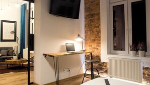 Una camera moderna con una scrivania in legno, un portatile e una TV montata a parete.