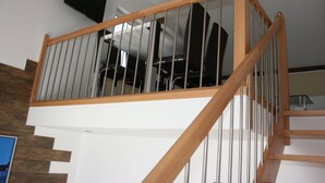 A modern staircase with wooden railings and metal balusters, leading to an upper floor. - Pension am Donaubogen (Barbing)