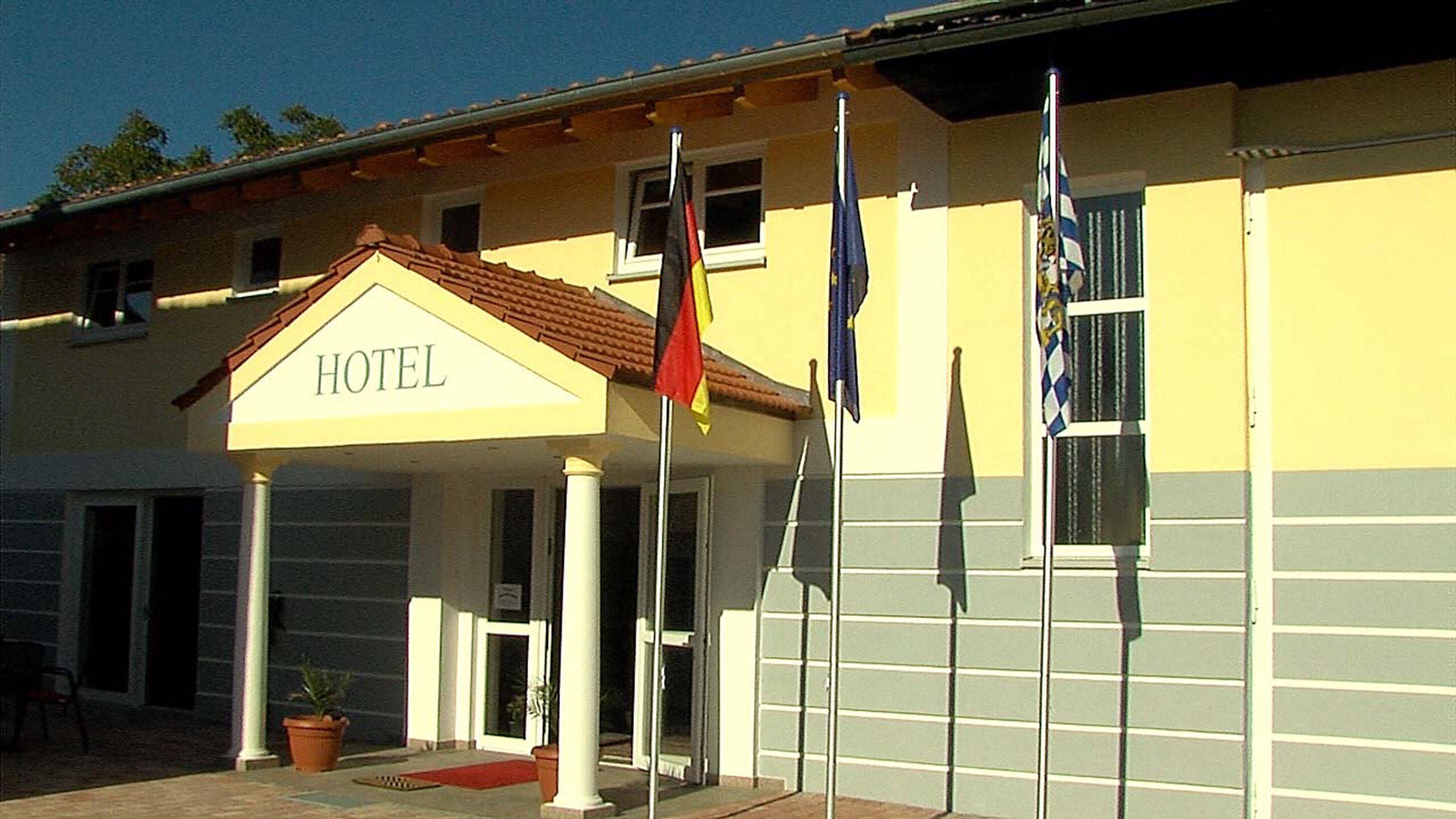 A hotel with a covered entrance, a sign reading "HOTEL", and multiple flags.