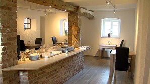 A modern kitchen with a brick accent wall, a breakfast bar, and a dining area with a table and chairs. - Pension am Donaubogen (Barbing)