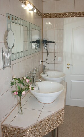 Een badkamer met twee wastafels, een spiegel en een haardroger.