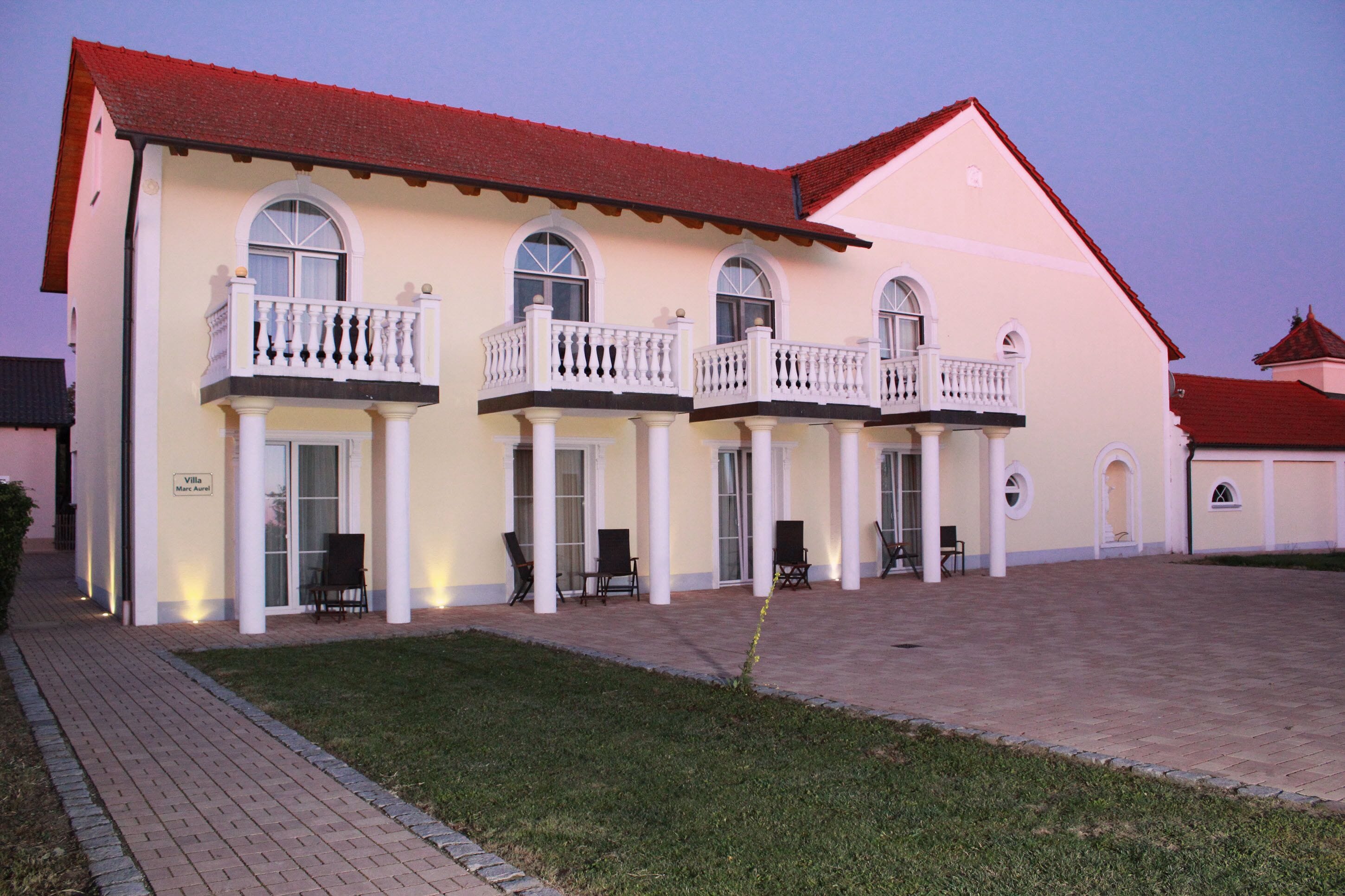 A large building with multiple balconies, a paved courtyard, and a sign indicating it is a villa.