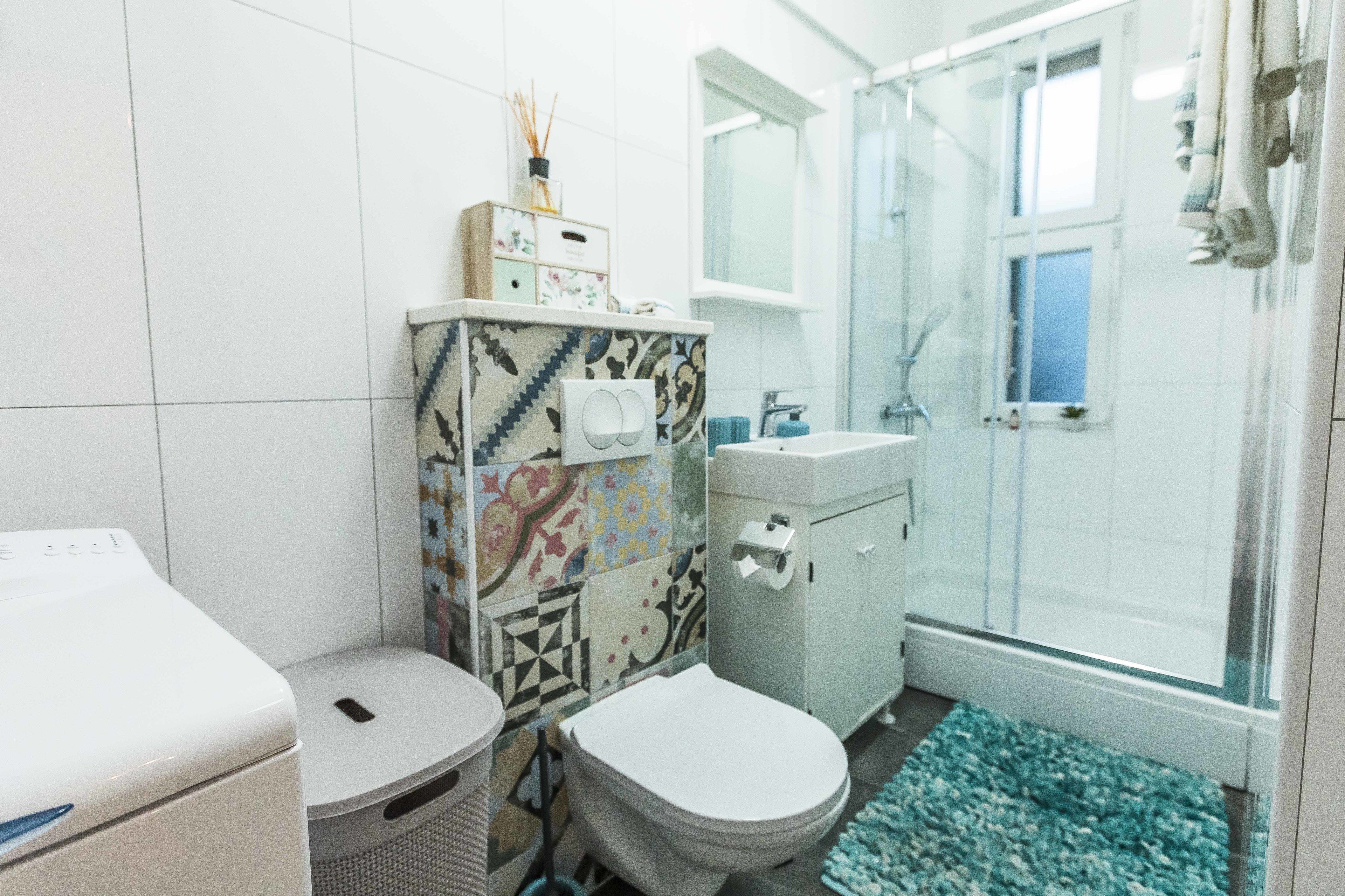 Ein Badezimmer mit Toilette, Waschmaschine, Dusche und Waschbecken.