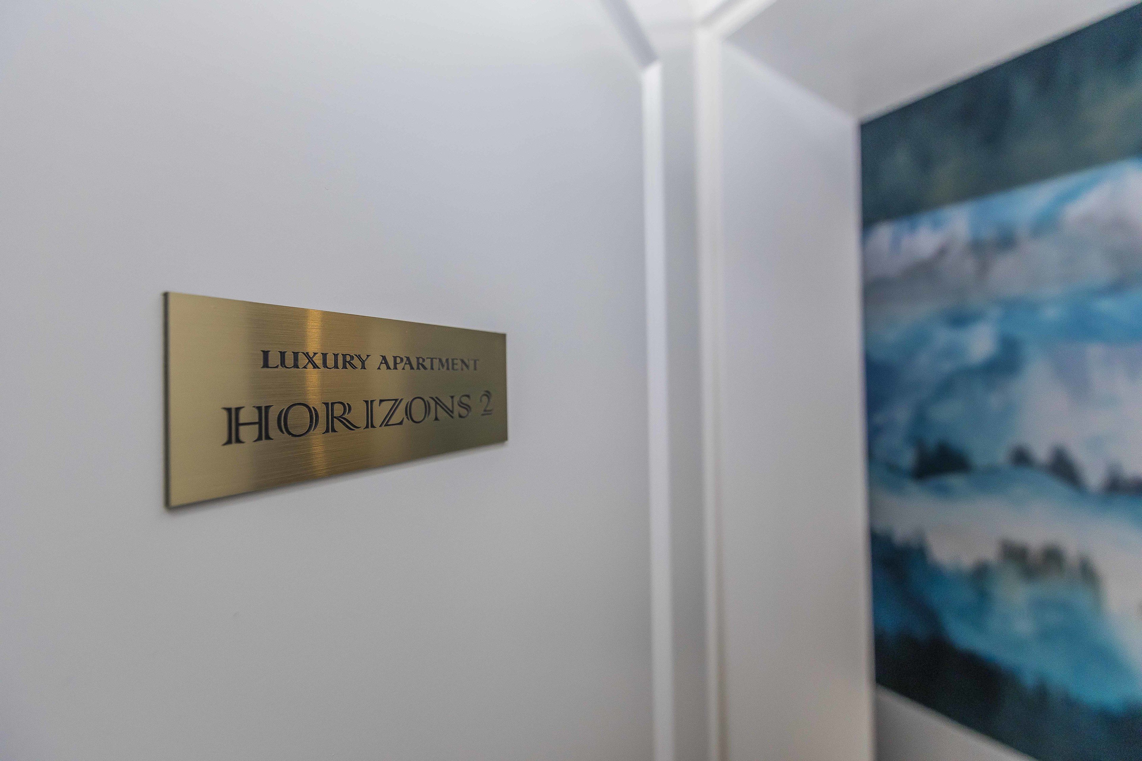 A sign for "Luxury Apartment Horizons 2" on a white wall.