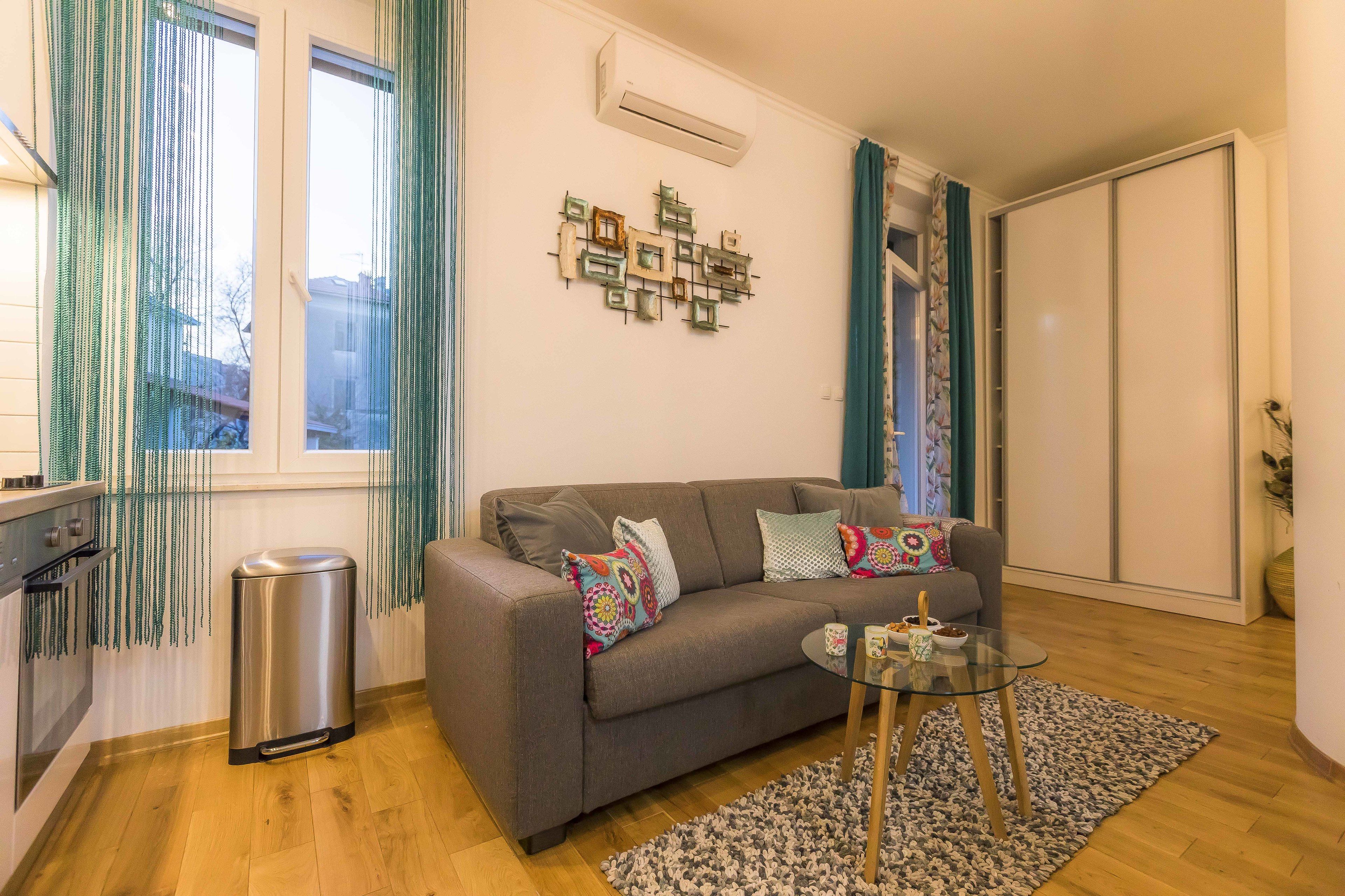 A living room with a sofa, a glass coffee table, and a patterned rug.