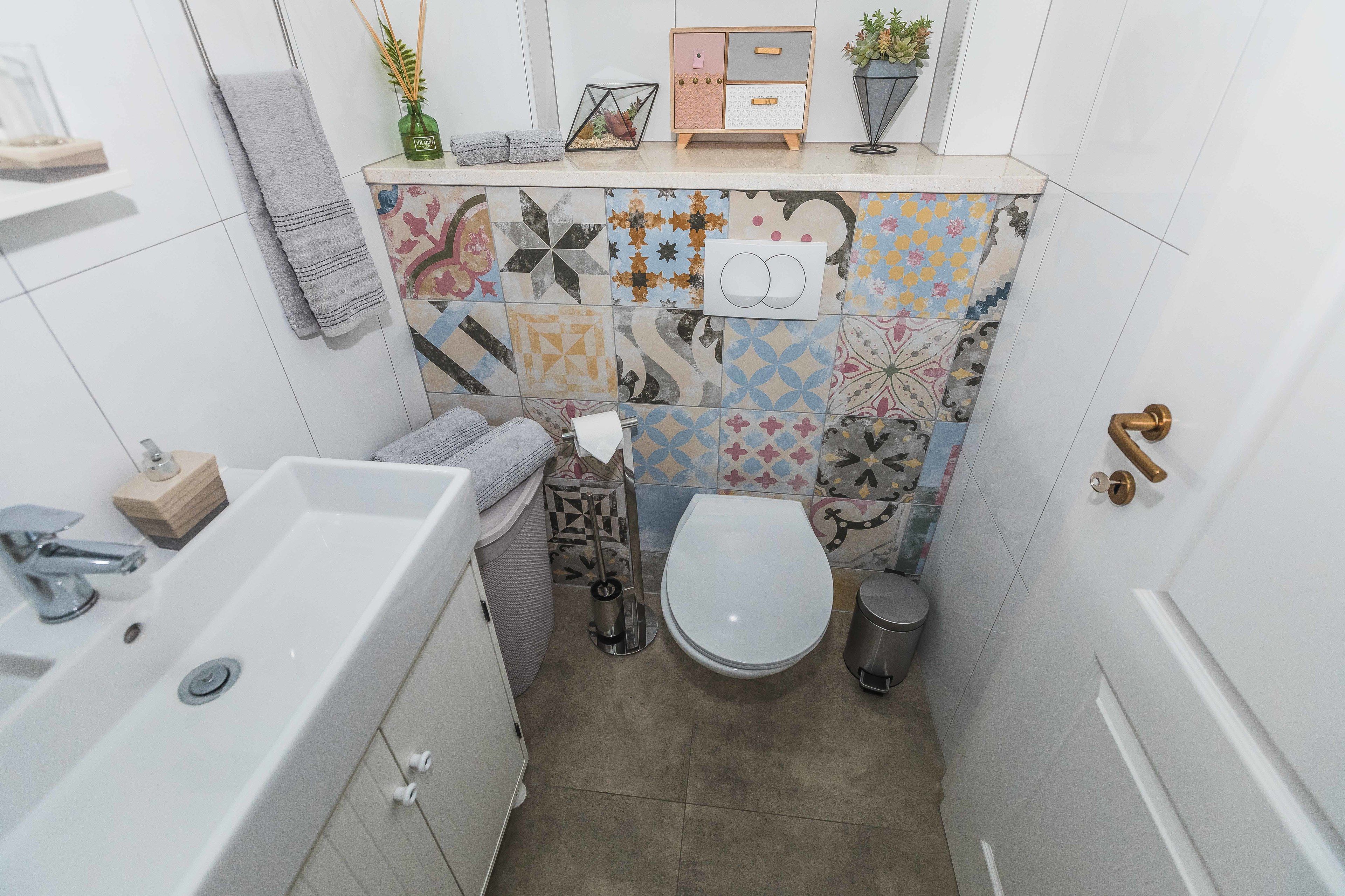 A small bathroom with a white sink, toilet, and a shower area.