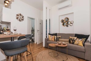 Uma sala de estar moderna com um sofá cinzento, uma mesa de jantar de madeira e uma mesinha de centro.