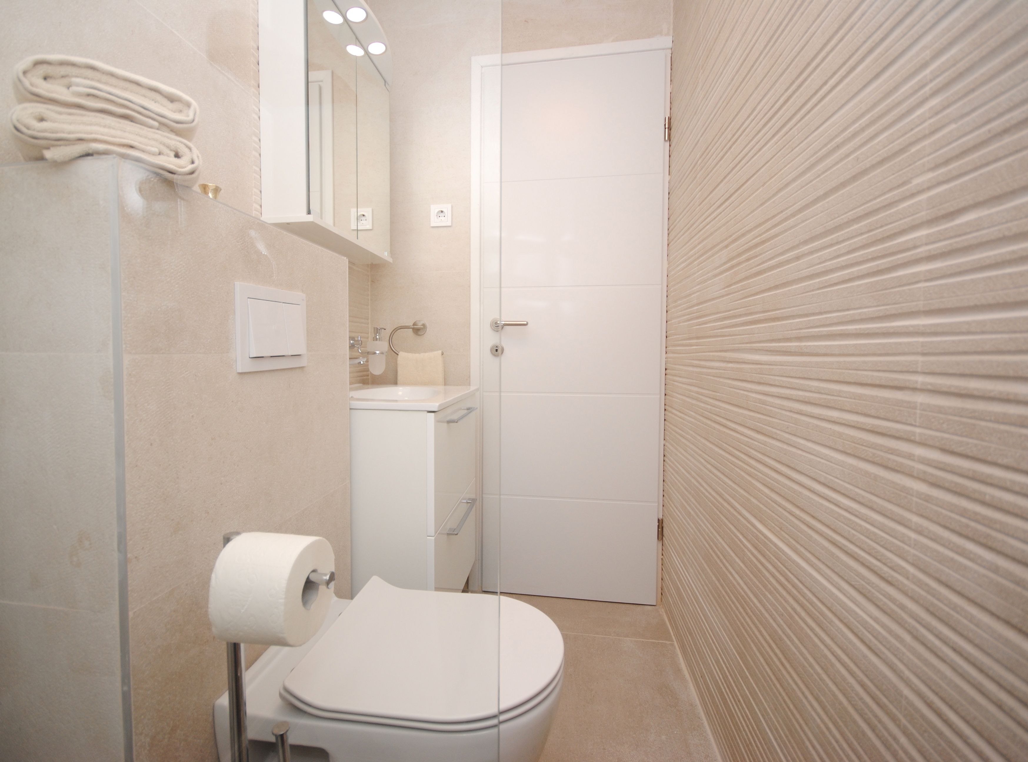 A modern bathroom with a toilet, sink, and towel rack.