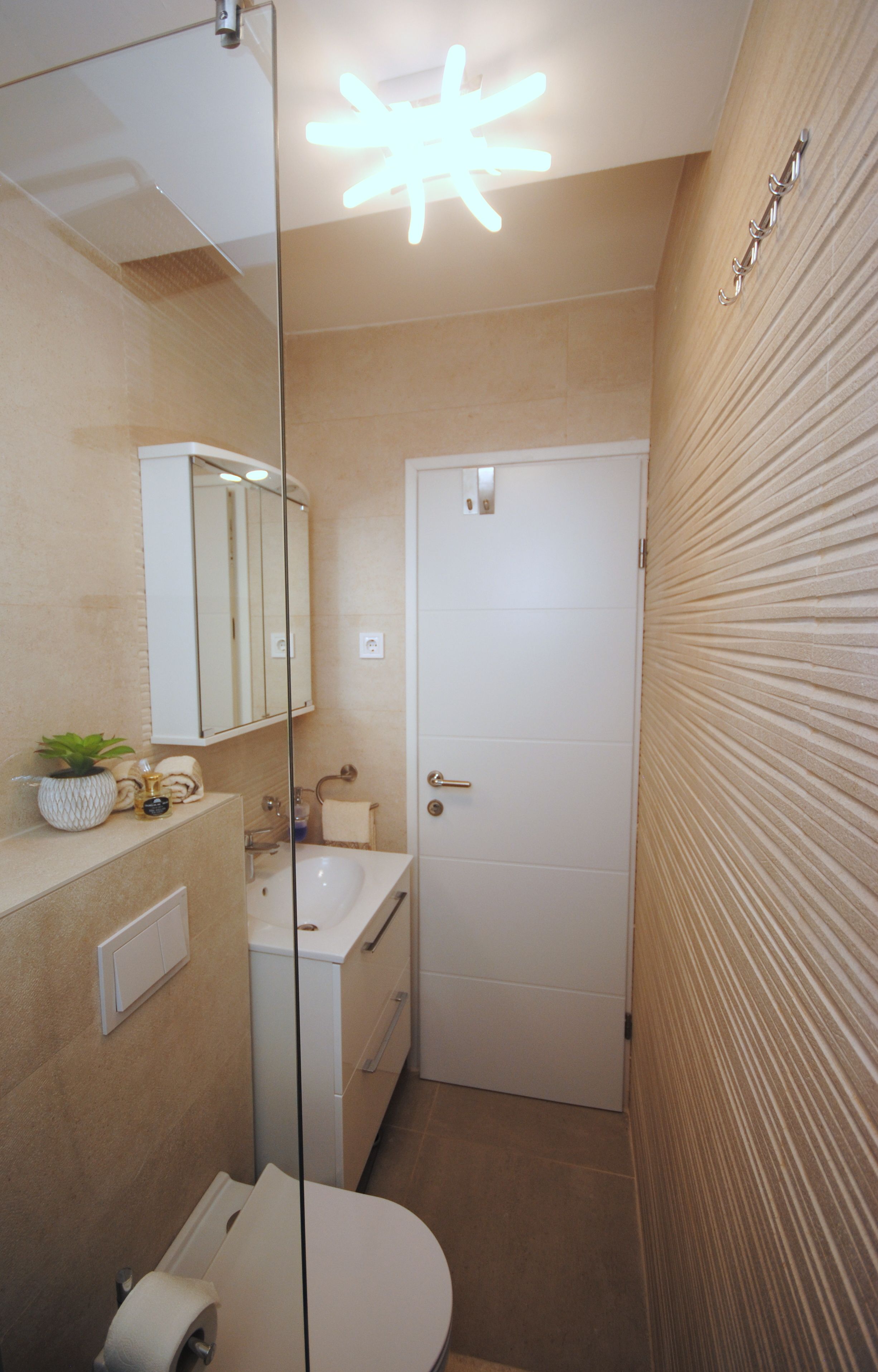 A compact bathroom with a white sink, mirror, and toilet.