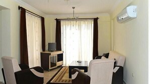 Ein Wohnzimmer mit Fernseher, einem kleinen Tisch und zwei Sesseln.