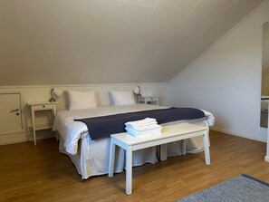Un dormitorio con cama, mesitas de noche, un escritorio y un banco.
