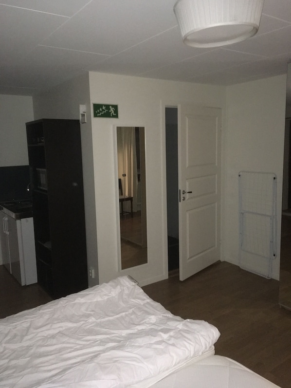 Una habitación de hotel con una cama, un armario, una puerta que da a otra habitación y un espejo.