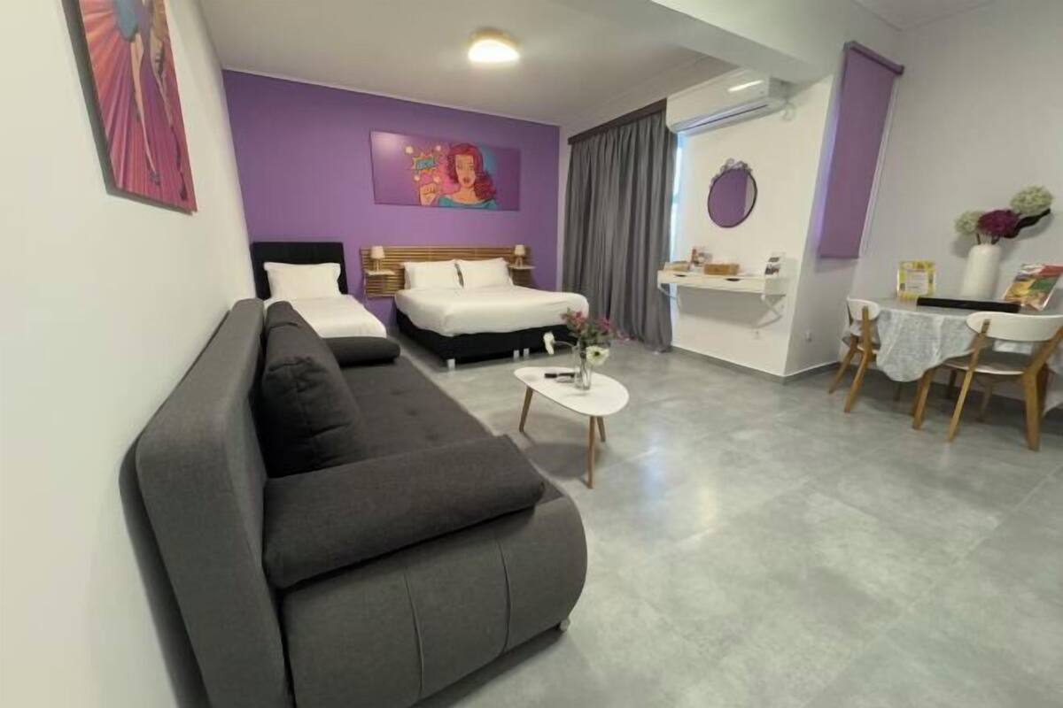 Una habitació d'hotel moderna amb un sofà, un llit, una taula petita i un escriptori amb una cadira.
