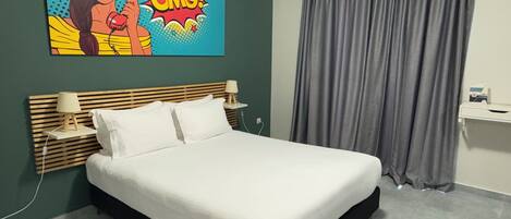 A modern hotel room with a large bed, two bedside tables with lamps, a grey curtain, and a colorful artwork on the wall.