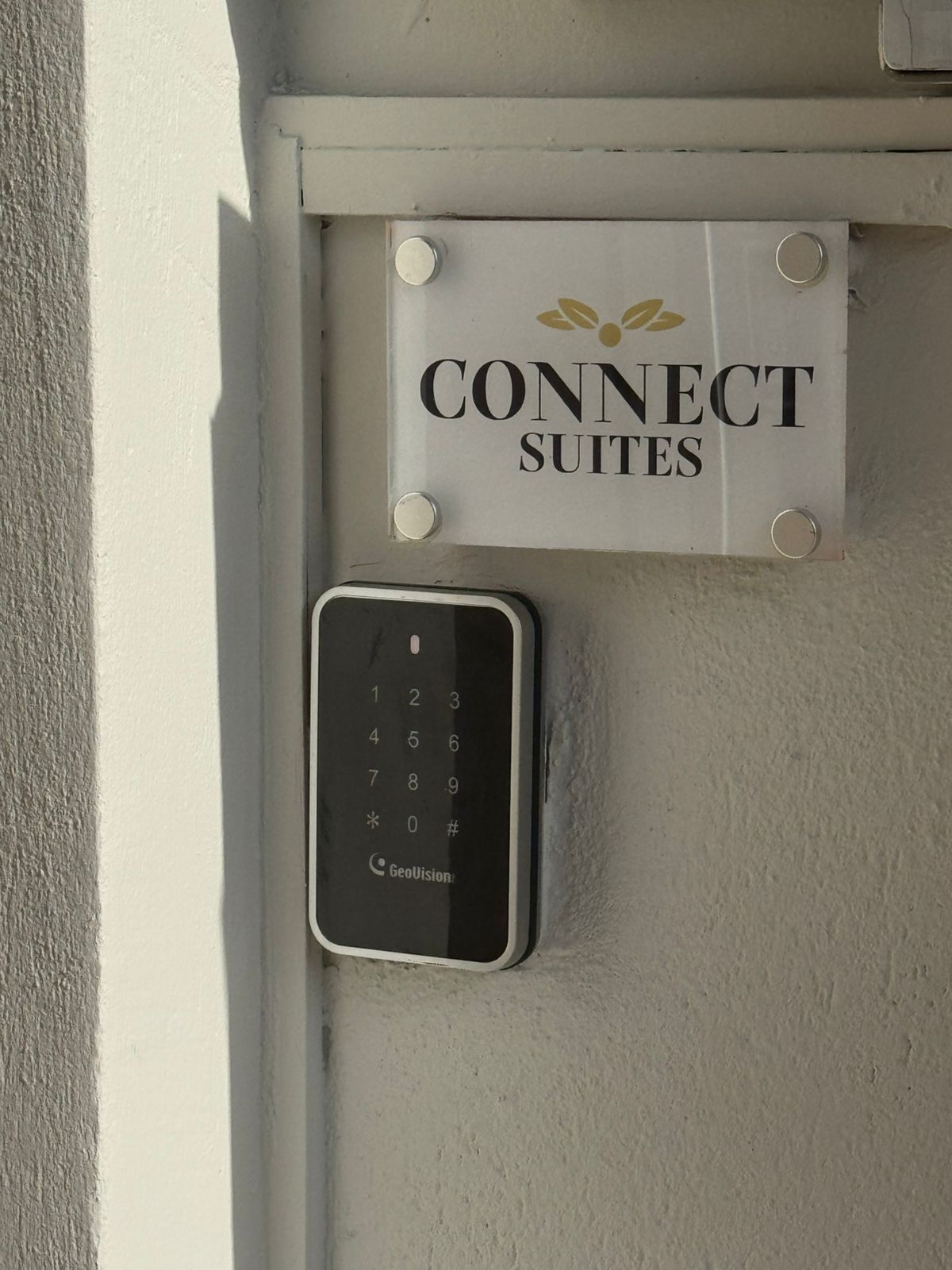 Placa com a inscrição 'CONNECT SUITES' e um dispositivo de teclado abaixo.