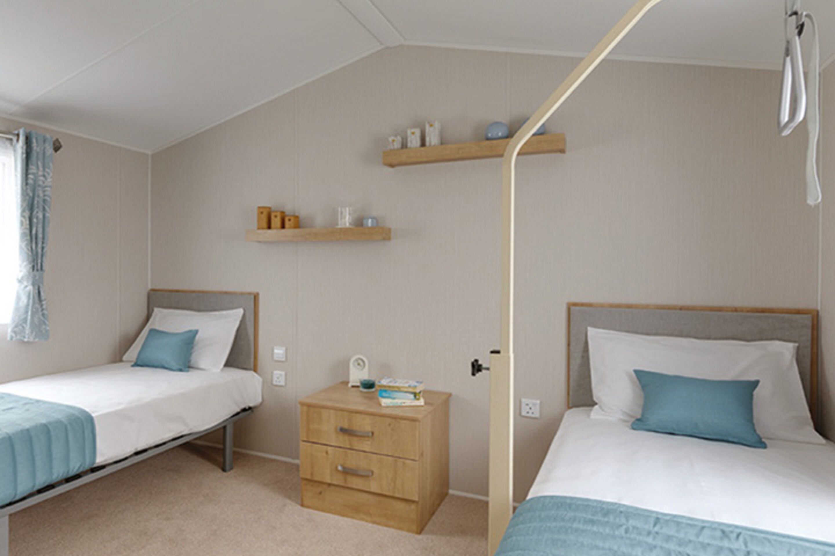 A bedroom with two single beds, a nightstand, and a shelf with toiletries.