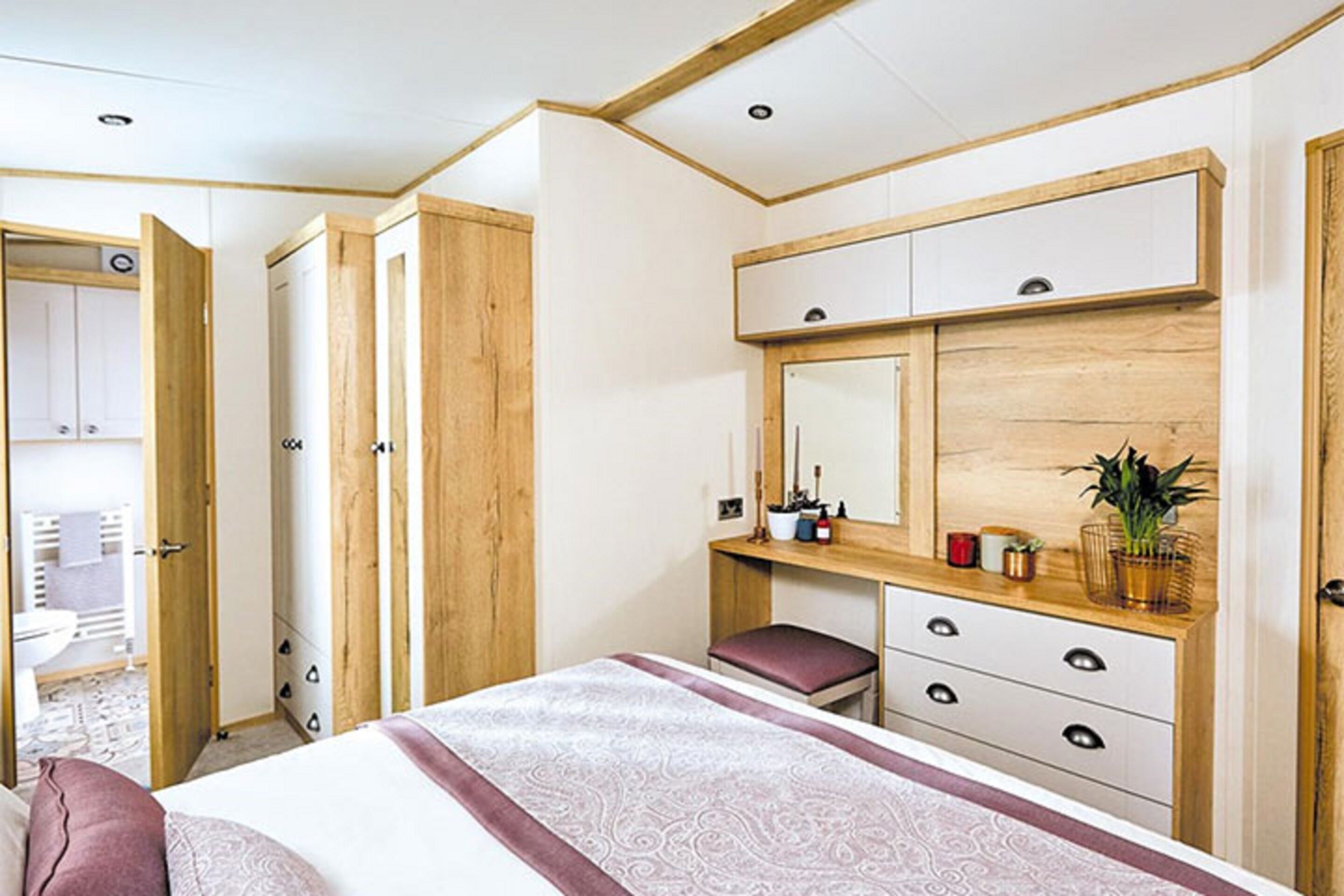 A bedroom with a bed, a wooden dresser, a mirror, and a bench.