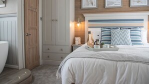 A bedroom with a bed, bedside table, and a wardrobe. - Newperran Holiday Resort (Truro)